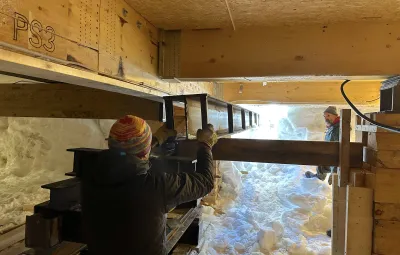 Carpenters guide metal I-beam udnerneath annex